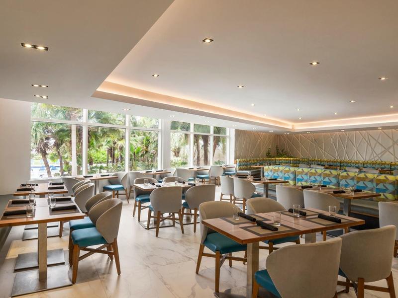 Jasna, nowoczesna restauracja z dużymi oknami i niebiesko-szarymi krzesłami.