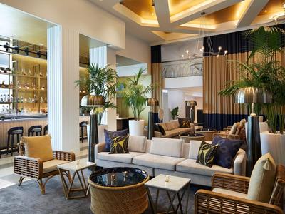 Moderner, heller Hotel-Loungebereich mit Sofas, Stühlen und grünen Pflanzen.