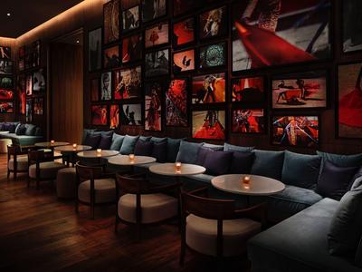 Gemütliche Lounge mit dunkler Holzboden, blauen Sofas und kunstvoll beleuchteten Wandbildern.