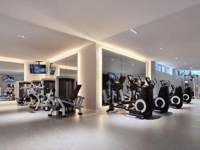 Moderner Fitnessraum mit verschiedenen Trainingsgeräten und heller Beleuchtung.