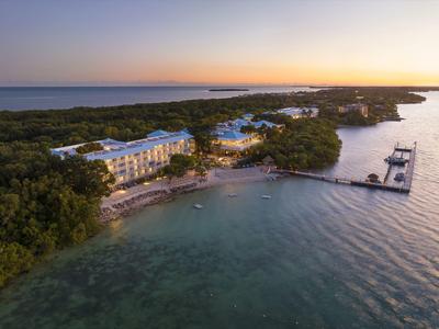 Luftaufnahme eines Resorts an einer Küste bei Sonnenuntergang mit Stränden und Bootsanlegern.
