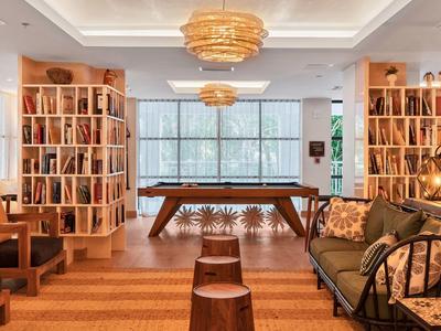 Gemütlicher Raum mit Holzregalen, Billardtisch, Sofa, Hockern und großen Fenstern.