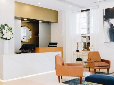 Heller Hotel-Lobby mit modernen Sesseln und Rezeption im Hintergrund.