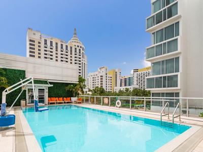 Moderner Pool auf der Dachterrasse eines Hotels mit Blick auf umliegende Hochhäuser.