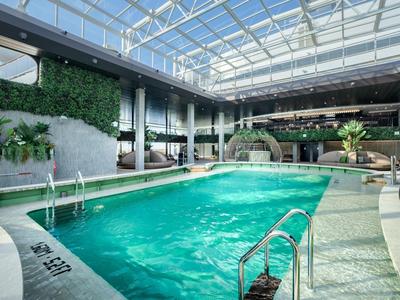 Helles Hallenbad mit Glasdach, grünen Pflanzen und moderner Einrichtung.