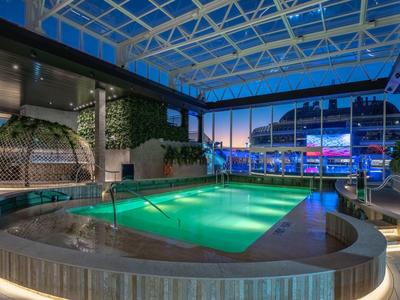 Innenpool mit beheiztem Wasser und Glasdach in einem modernen Hotel bei Abenddämmerung.