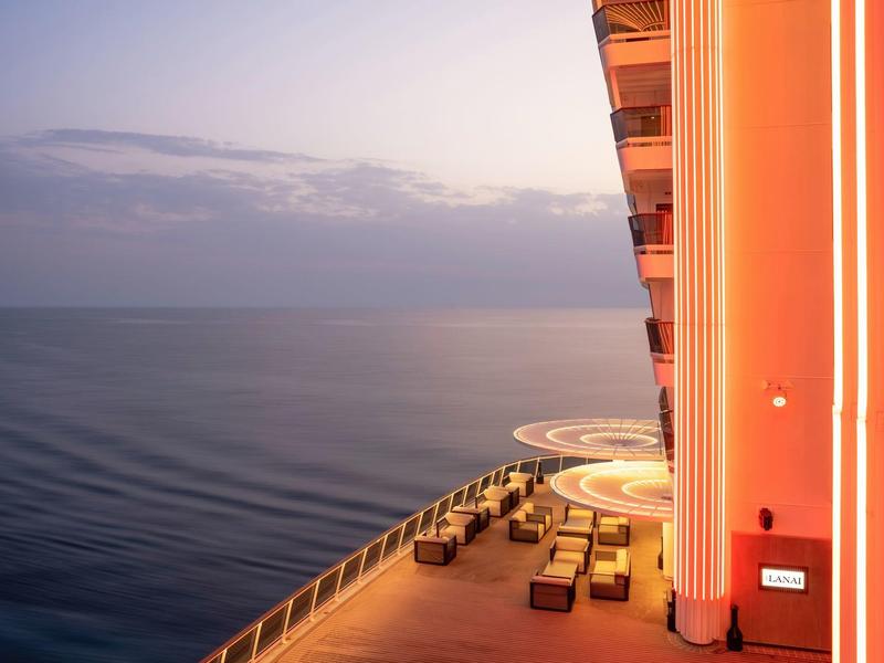 Hotelterrasse mit Sitzgelegenheiten und Meerblick bei Sonnenuntergang.