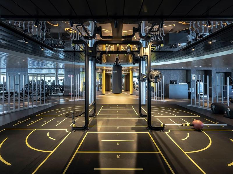 Moderner Fitnessbereich mit reflektierender Decke und markiertem Boden.