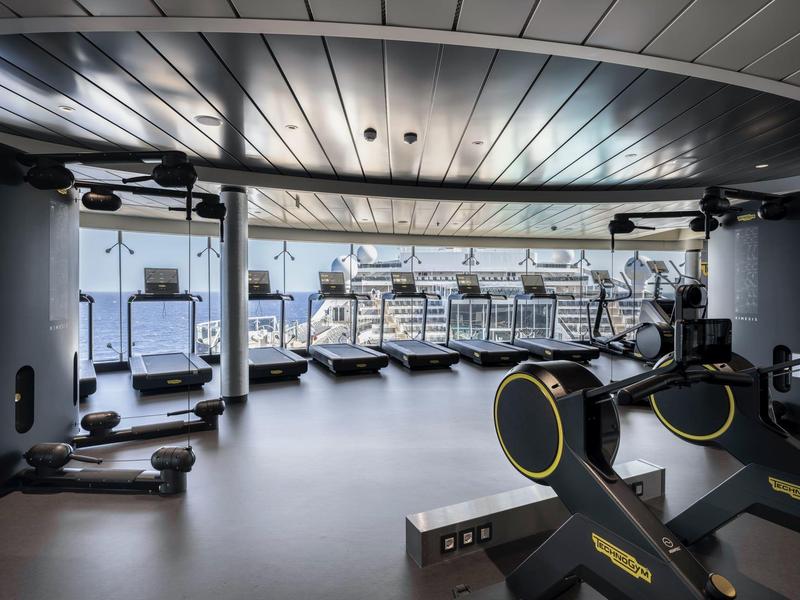 Moderner Fitnessraum mit Ausblick auf die Stadt, ausgestattet mit Laufbändern und Fitnessgeräten.