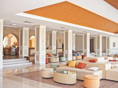 Großer Hotel-Loungebereich mit komfortablen Sofas, Sitzhockern und warmem Farbschema.