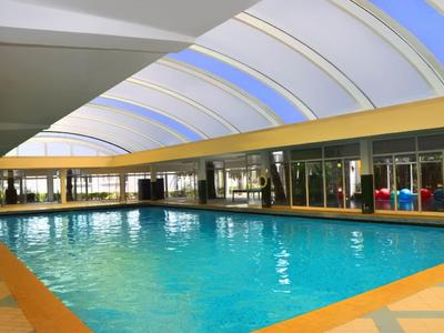 Großes Hallenbad mit Glasdach und Sitzbereich in einem Hotel.