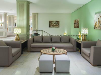 Helle, moderne Hotellounge mit grauen Sofas, grünen Wänden und dekorativen Bildern.