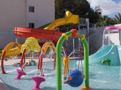 Kinderwasserrutsche mit verschiedenen bunten Wasserspielen in einem Hotelpoolbereich.