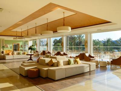 Jasny salon hotelowy z dużymi oknami, wygodnymi sofami i nowoczesnym wystrojem.