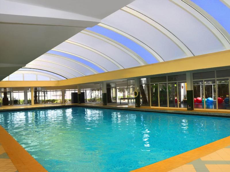 Großes Hallenbad mit Glasdach und Sitzbereich in einem Hotel.