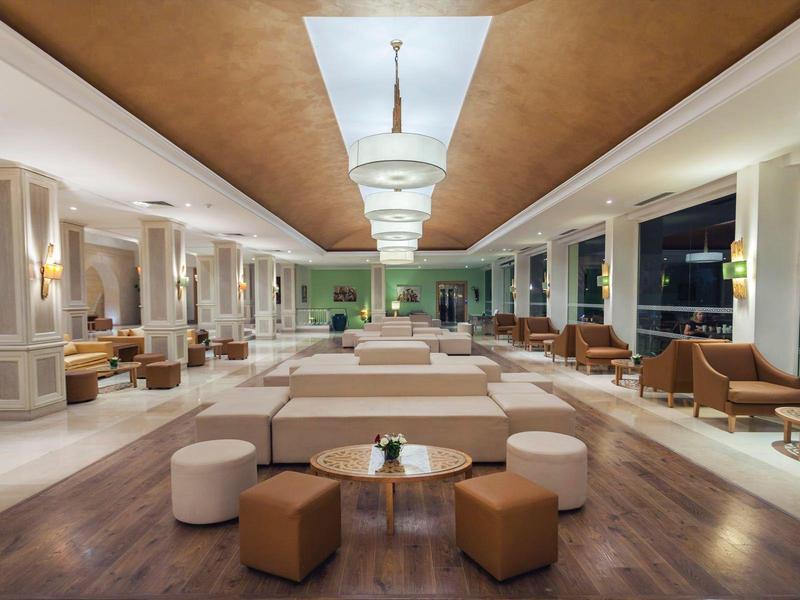 Große, moderne Hotellobby mit Sitzbereichen und stilvollem Design in warmen Farben.