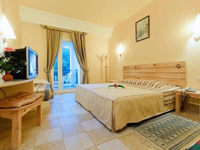 Helles Hotelzimmer mit Doppelbett, Flachbildfernseher und Zugang zu einem Balkon.