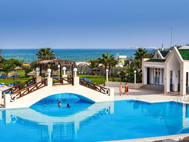 Großer Pool mit Brücke und Meerblick in einem Hotelresort.