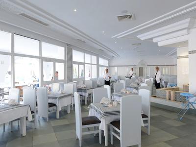 Helles, modernes Restaurant mit weißen Stühlen, gedeckten Tischen und großen Fenstern für Tageslicht.