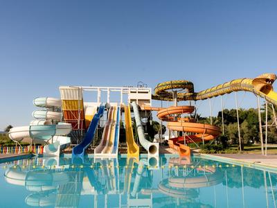 Mehrere bunte Wasserrutschen über einem klaren Pool unter blauem Himmel.
