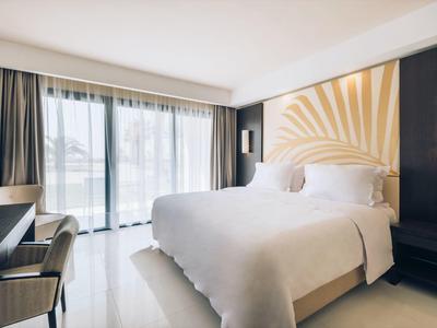Helles, modernes Schlafzimmer mit großem Bett, weißer Bettwäsche und bodentiefen Fenstern.