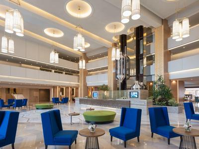 Grand hall d'hôtel moderne avec chaises bleues et sol en marbre clair.