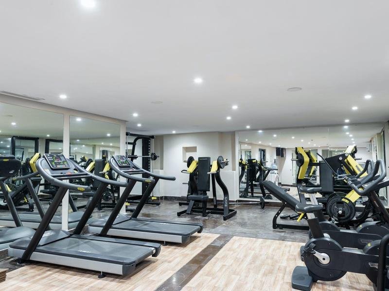 Salle de sport moderne avec tapis de course et vélos stationnaires dans un hôtel.