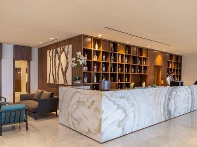 Moderner Empfangsbereich mit großem weißen Marmortresen und Holzregalen im Hintergrund.