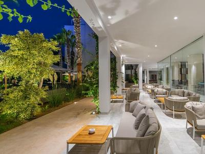 Moderner Außenbereich mit gemütlichen Sesseln, gläserner Wand und beleuchtetem Garten bei Nacht.