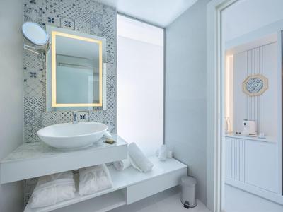 Moderní koupelna se osvětleným zrcadlem, umyvadlem a ručníky.