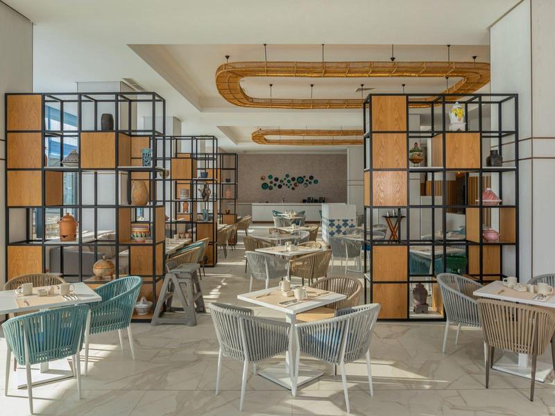 Moderní kavárna se stylovými židlemi a dekorativními regály v teplé atmosféře.