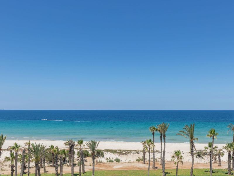 Pláž s palmami a jasně modrou oblohou u moře