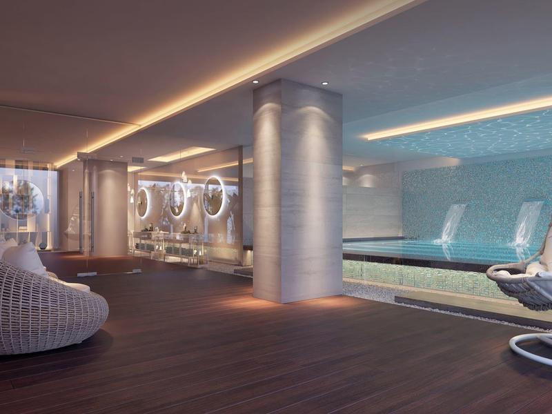 Moderní vnitřní bazénová zóna s závěsným křeslem, kulatými sedadly a jemným osvětlením.