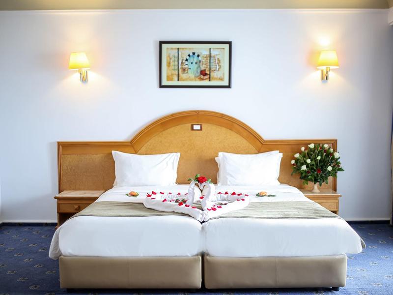 Moderne hotelkamer met twee eenpersoonsbedden, nachtkastjes, wandlampen en een bloemenboeket.