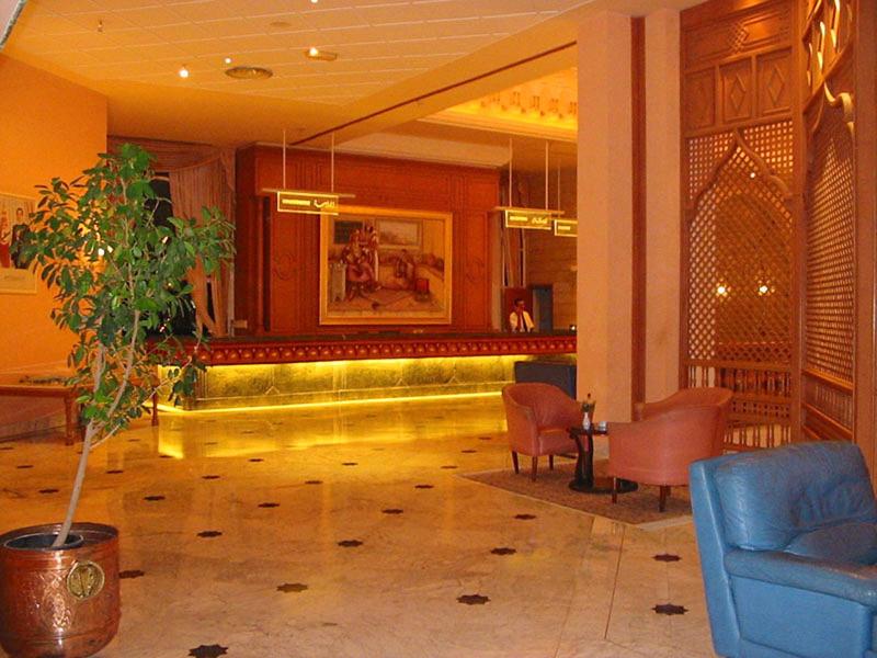 Warme hotelreceptie met verlichte balie en zitplaatsen.