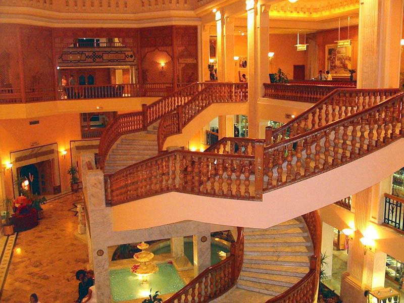 Ruime, elegante hotellobby met marmeren vloeren en gebogen trappen.