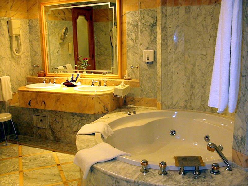 Luxe badkamer met ronde badkuip en marmeren wastafel in warm licht.