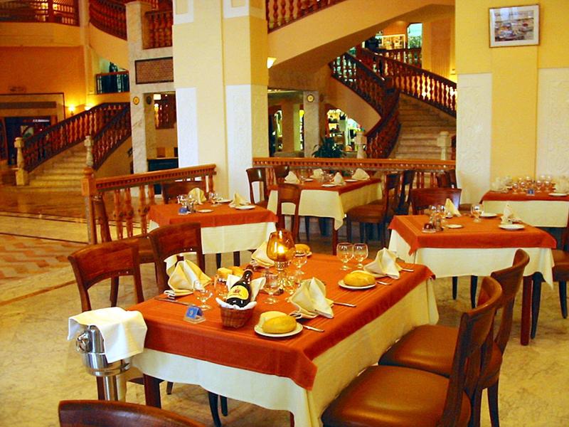 Elegante ontbijtruimte met gedekte tafels en een wenteltrap op de achtergrond.