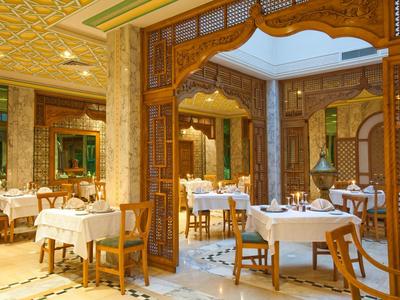 Elegantes Hotelrestaurant mit Holzmöbeln und weiß gedeckten Tischen in warm beleuchtetem Raum.