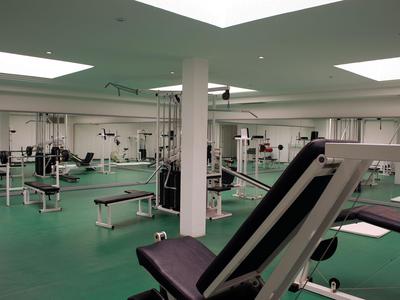 Grande palestra con varie attrezzature per allenamento e pavimento verde.