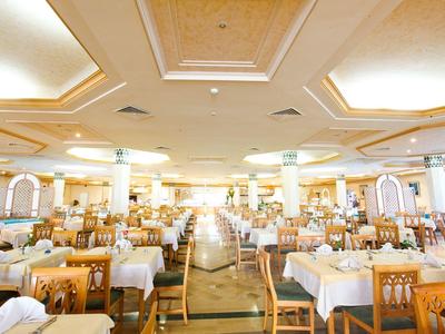 Großer, heller Speisesaal mit vielen Holztischen und weißen Tischdecken.