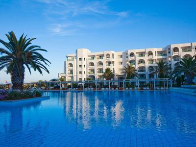 Grande hotel con piscina blu e palme sotto un cielo limpido
