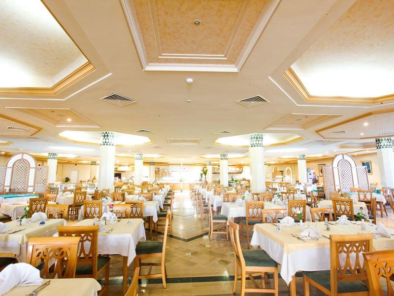 Großer, heller Speisesaal mit vielen Holztischen und weißen Tischdecken.