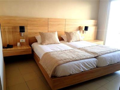 Chambre d'hôtel moderne avec deux lits simples et grandes fenêtres.