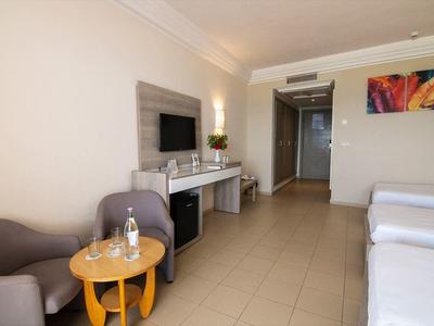 Chambre d'hôtel moderne avec deux lits, fauteuils, table et bureau équipé d'une télévision.