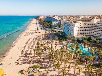 Vue aérienne d'une plage avec des hôtels, des palmiers et une piscine le long de la côte