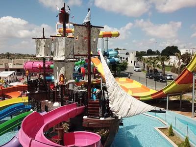 Bunter Wasserpark mit Rutschen, Pools und einem Piratenschiff unter blauem Himmel.