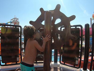 Kinder spielen auf einem Outdoor-Spielplatz mit mehreren Paneelen und einer großen Holzstruktur.