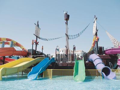Bunte Wasserrutschen und Klettergerüste in einem Wasserpark bei klarem Himmel.