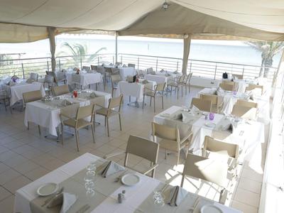 Helles, überdachtes Restaurant mit weißen Tischdecken und Meerblick.